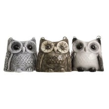 Different-colored ceramic sauna owls side by side.